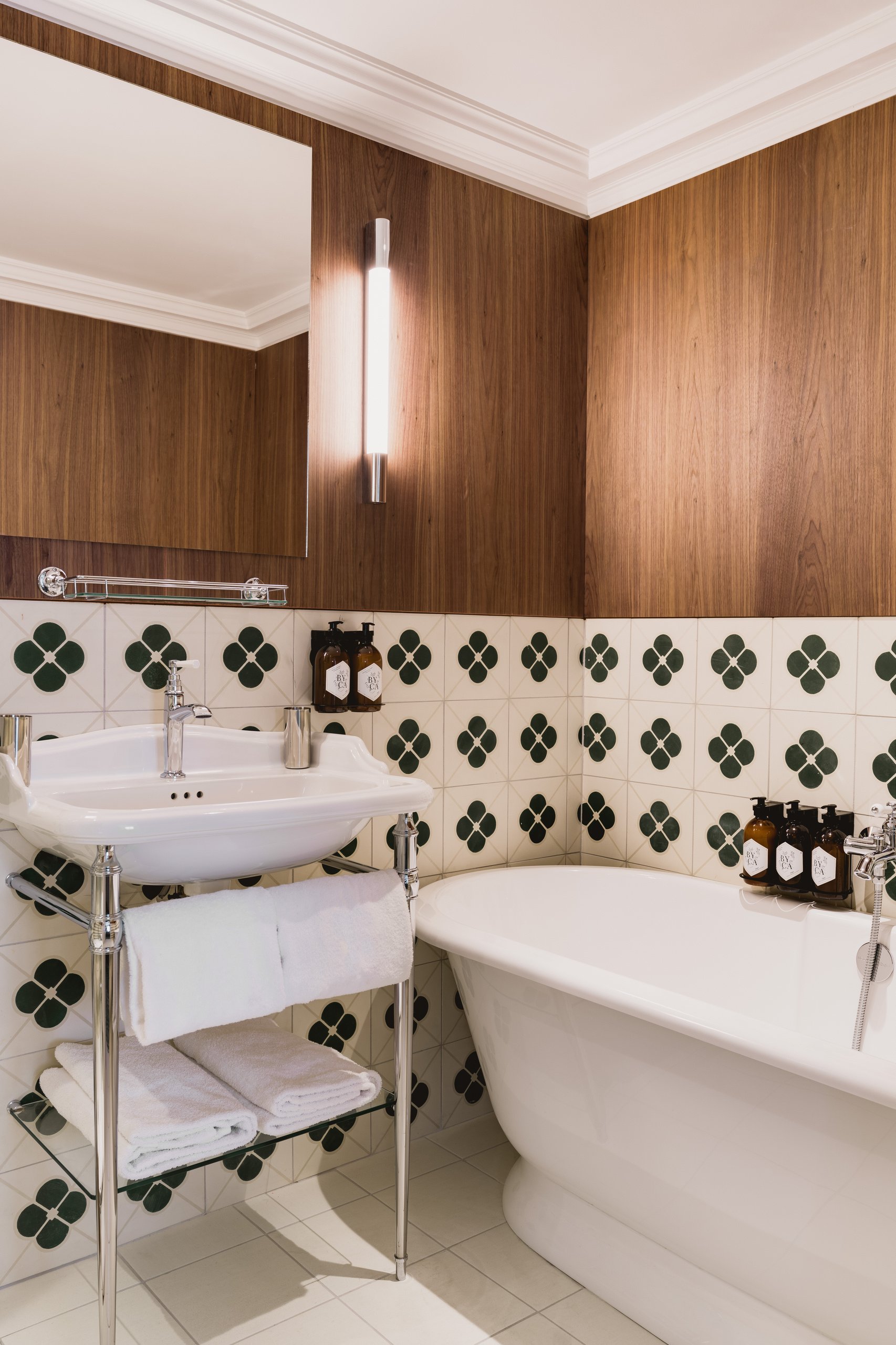 Chambre d'hôtel avec lit queen-size, salle de bain attenante et boiseries en noyer clair.
