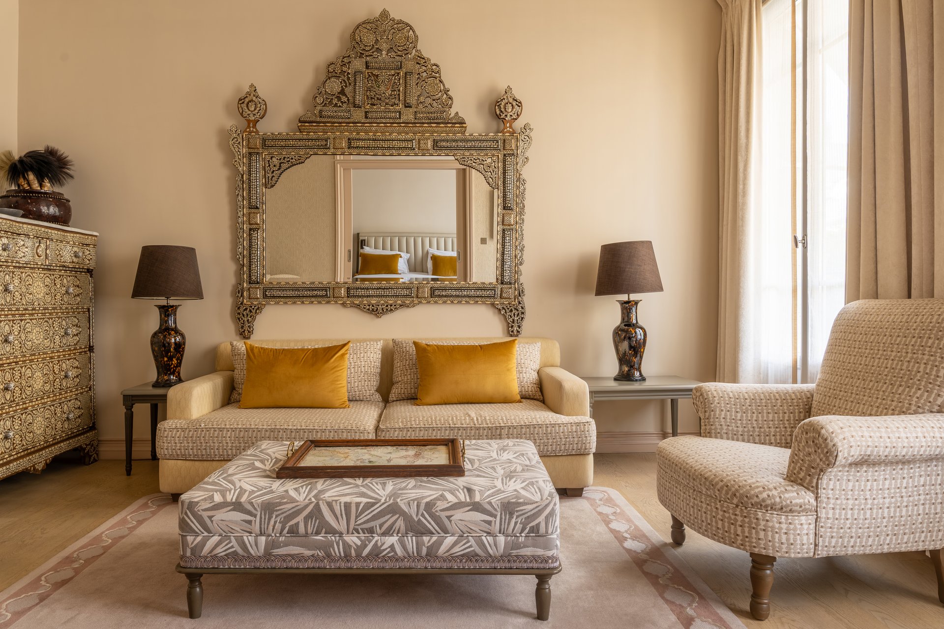 Suite luxueuse avec salon séparé, chambre à coucher visible par portes ouvertes, mobilier élégant et télévision murale.