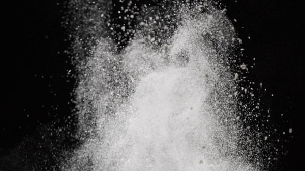 Close-up of dust particles rising from below against a black background 4K