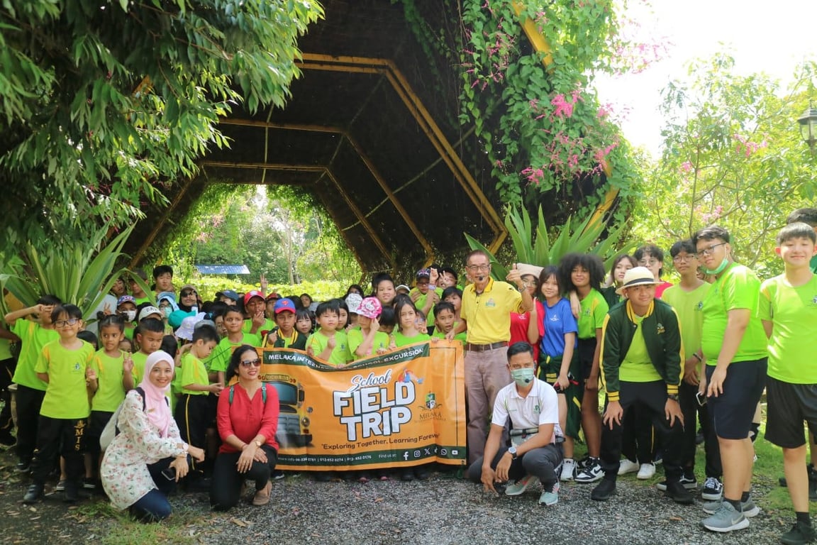 Students and staff pose for a group photo during an outdoor field trip to a bee farm.