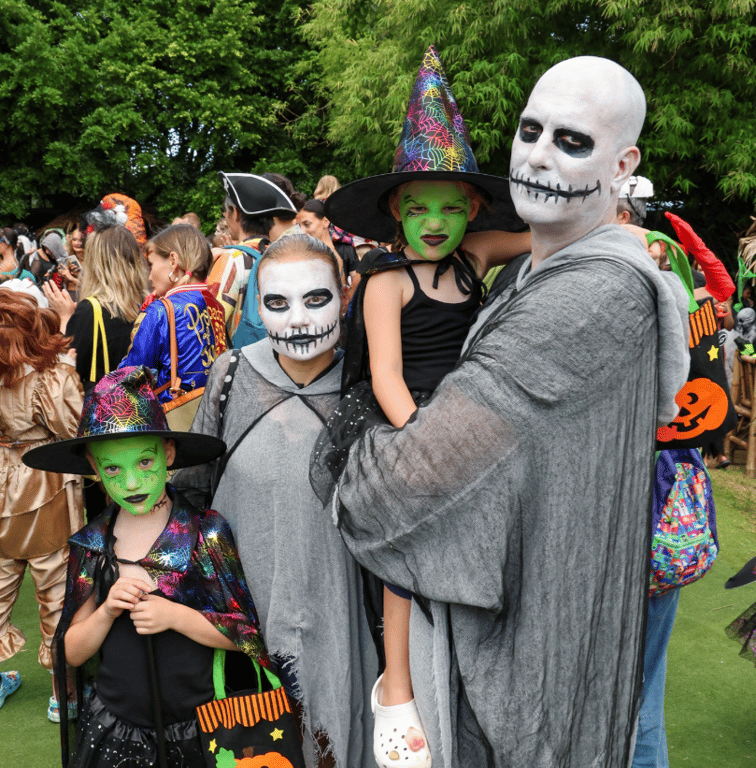 Families dressed up in spooky costumes for Halloween celebration.