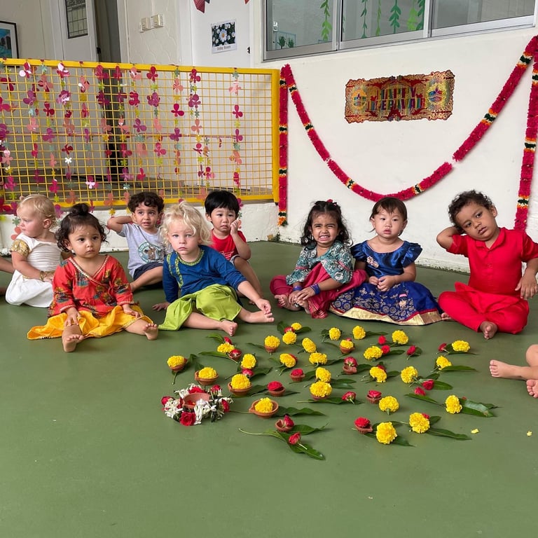 Children dressed in colorful traditional attire celebrate Deepavali with flowers and smiles.
