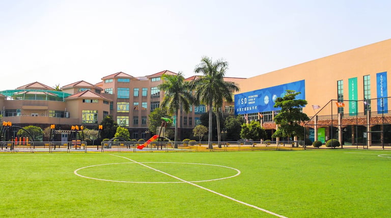The green athletic field and primary campus buildings at International School of Dongguan.