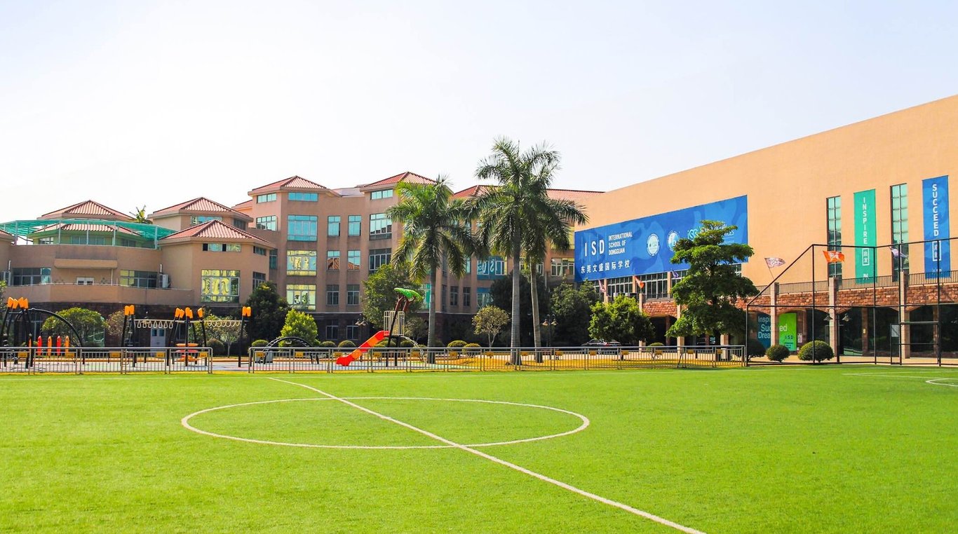 The green athletic field and primary campus buildings at International School of Dongguan.