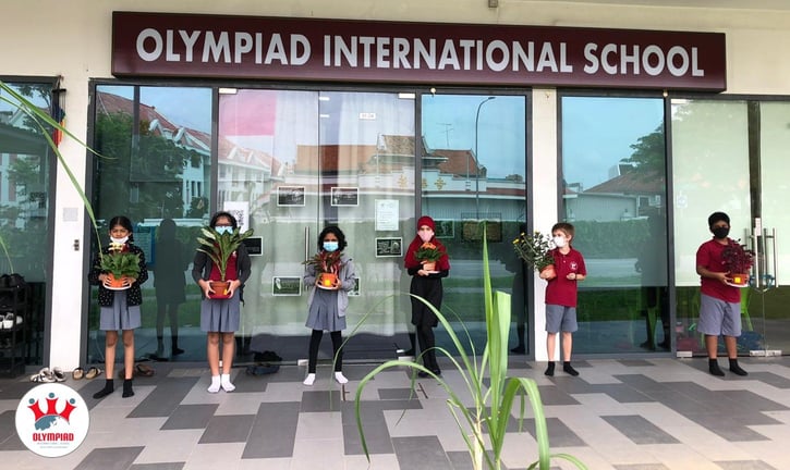 Students showing off their plant projects in front of the school building