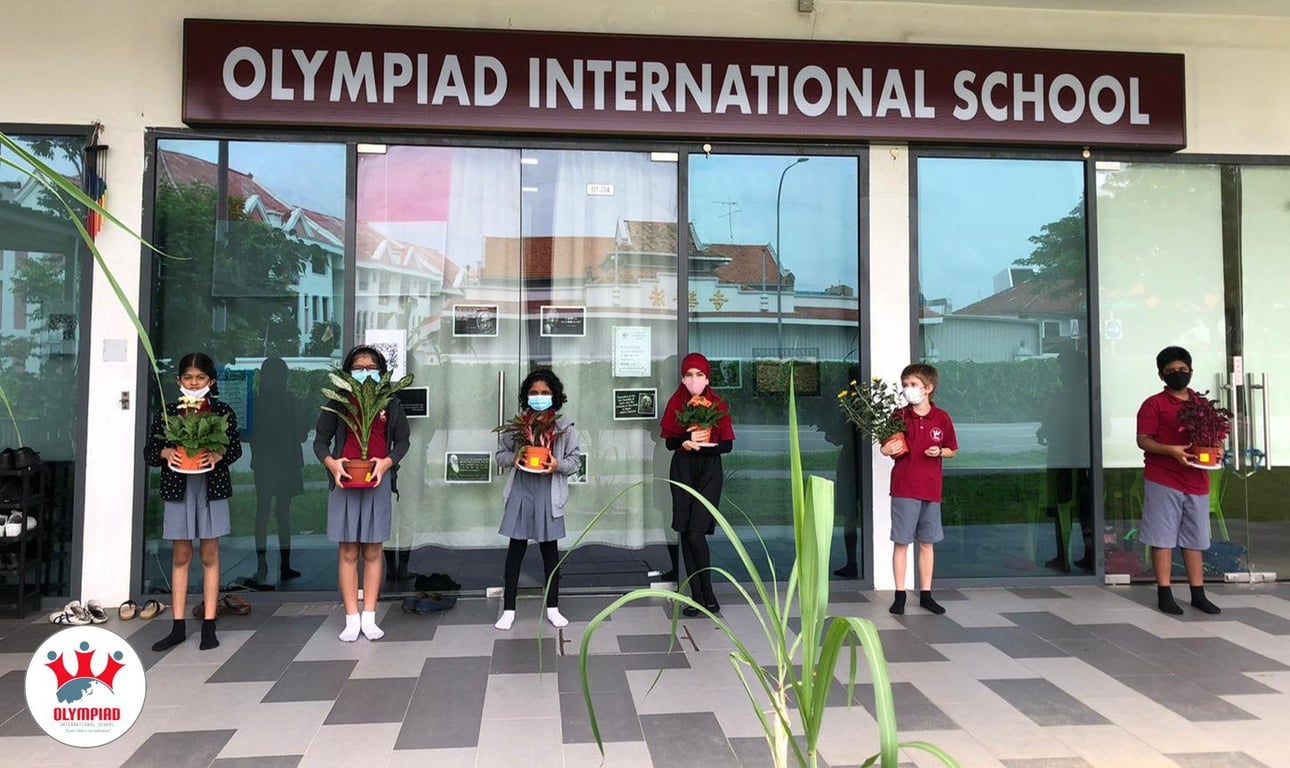 Students showing off their plant projects in front of the school building