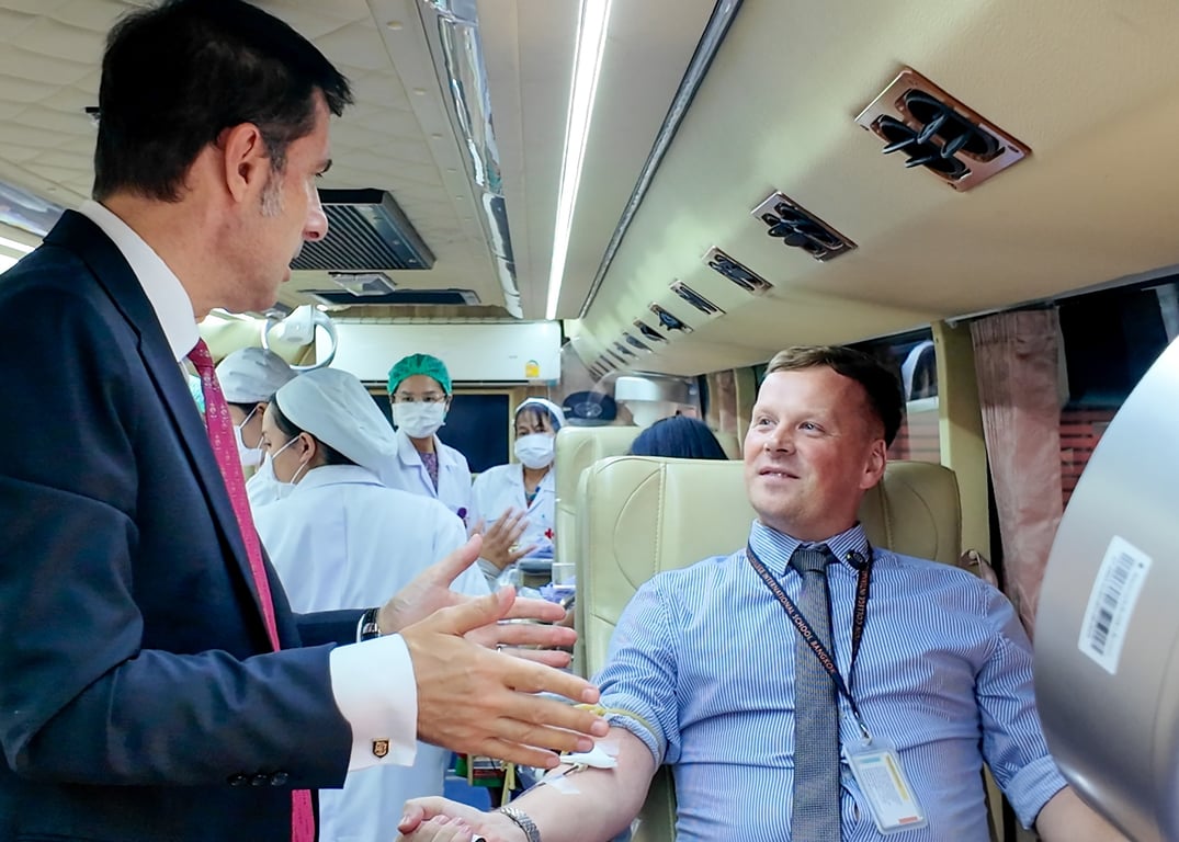 Staff member donating blood during the Thai Red Cross visit.
