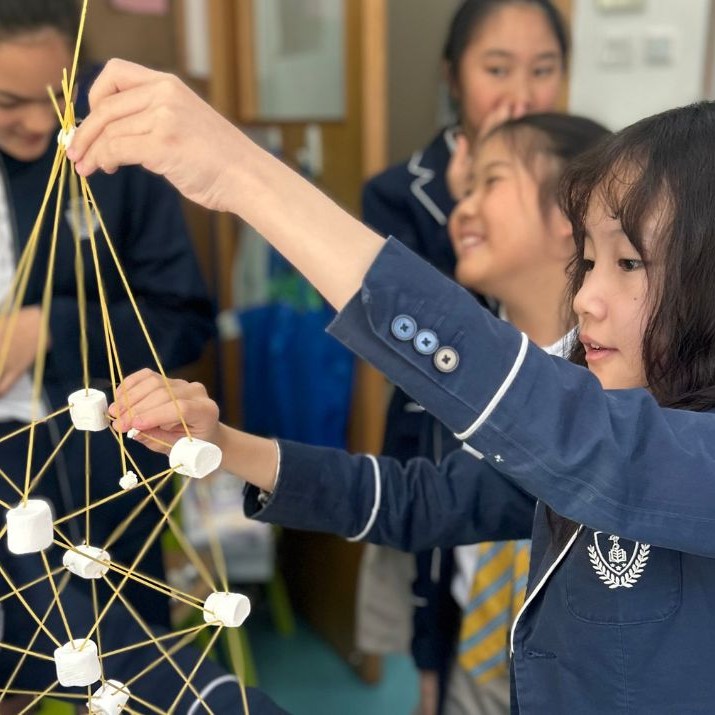 Students building a marshmallow and spaghetti tower during a classroom activity.