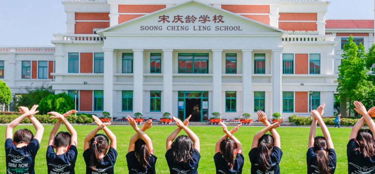 A view of the main academic building overlooking a green field.
