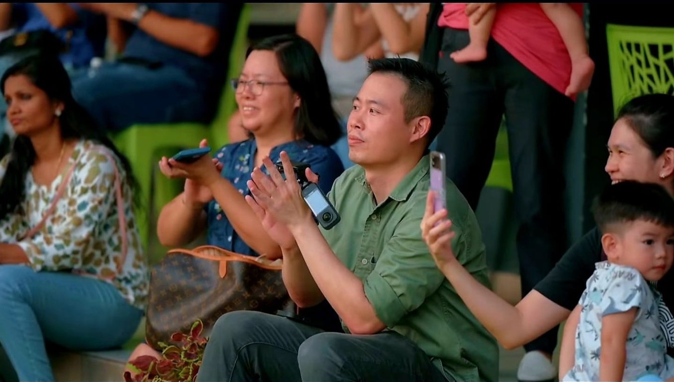 Parents applauding and taking photos during a school event