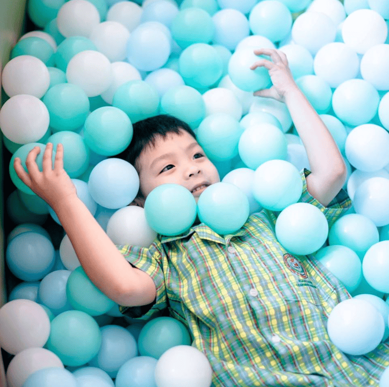 A student playing in a ball pit.