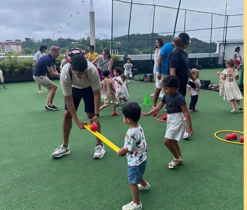 Parent guiding preschooler through ball activity at Sports Day.
