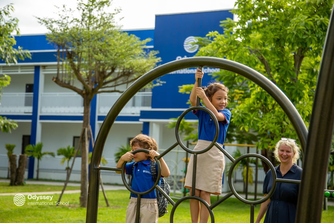 Young students play on outdoor climbing equipment under a teacher’s supervision.