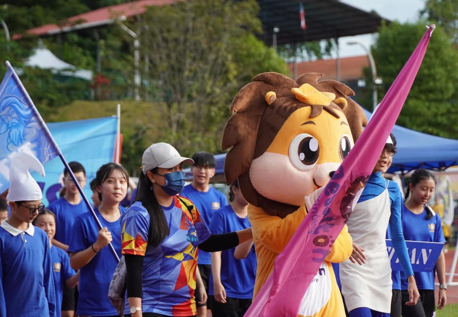 Students proudly march in a school parade led by the school mascot, showcasing vibrant house spirit and camaraderie during Sports Day.