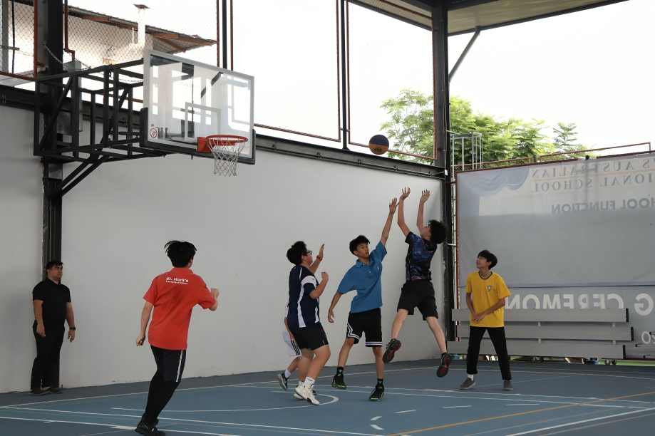 Secondary students play basketball in the school gym.