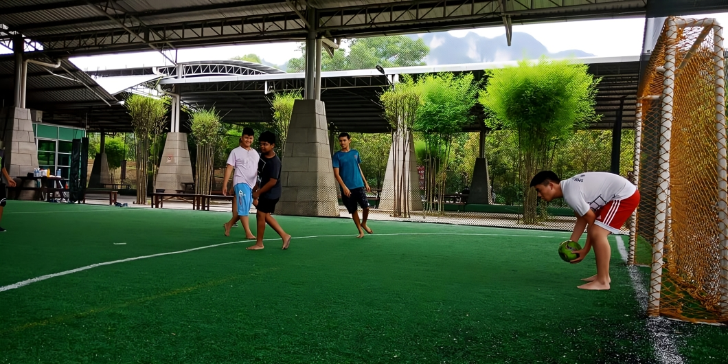 Students playing football in the covered outdoor field after school.