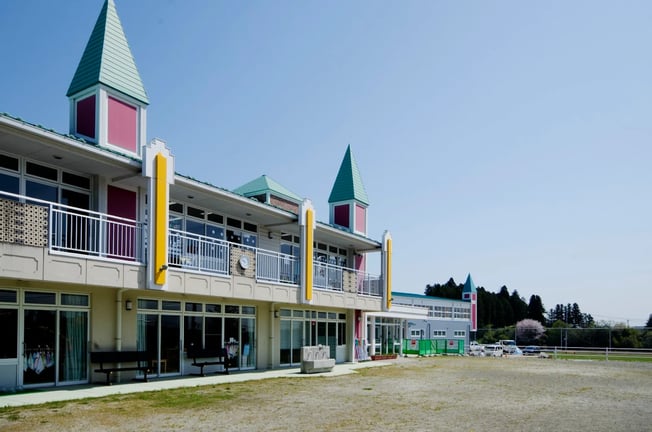 An exterior view of the colorful Horizon Academy Sendai Campus and primary school field.