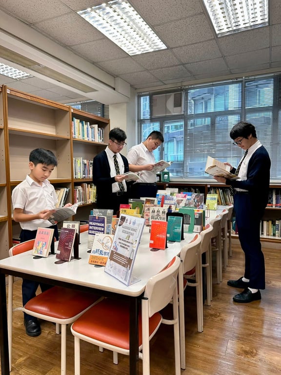Students reading books around a display table in the school library.