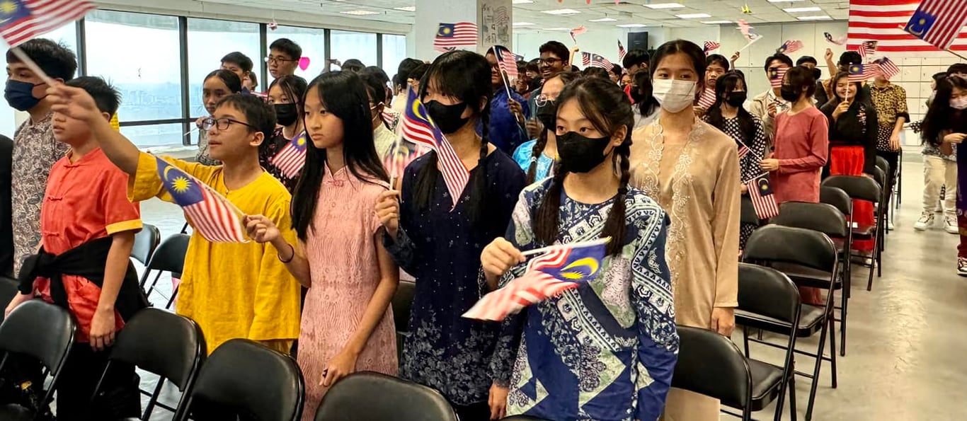 Students in traditional attire holding Malaysian flags.