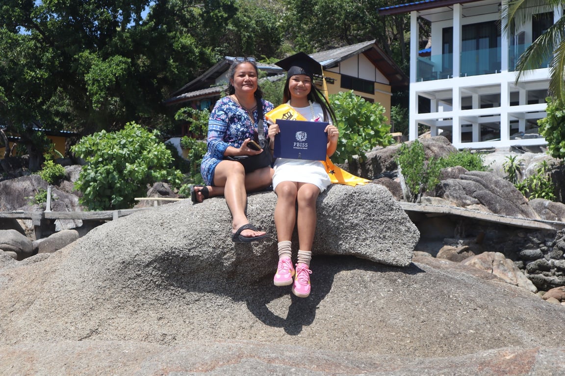 A PBISS graduate celebrates receiving her diploma with family by the beach.