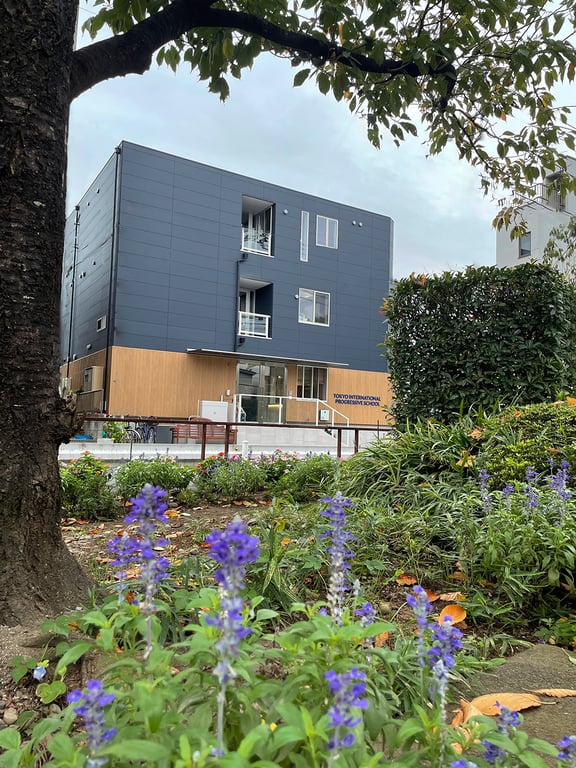 Tokyo International Progressive School campus surrounded by greenery and seasonal flowers.