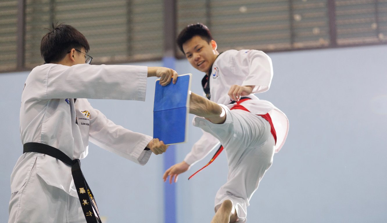 Student breaking a board with a powerful taekwondo kick.