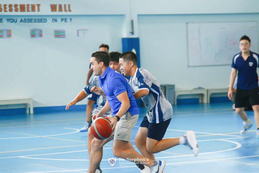 Teachers challenging secondary students in a lunchtime basketball game.