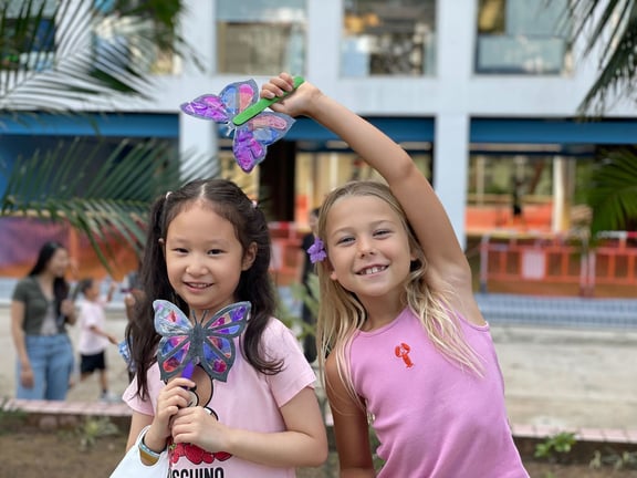 Primary students showing their colourful butterfly creations.