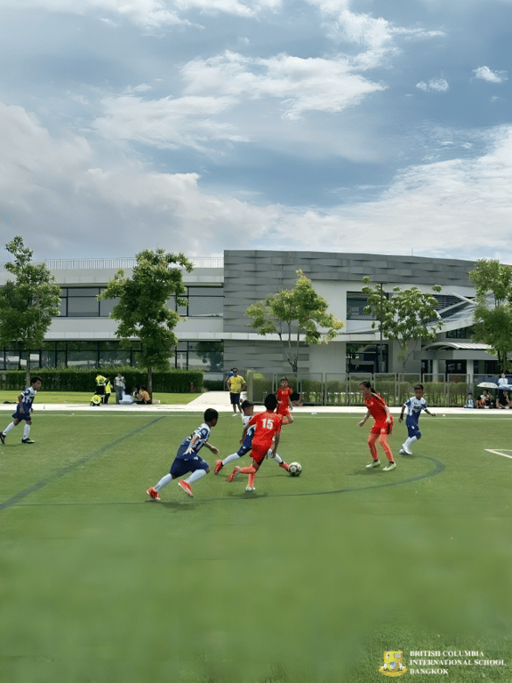 Teams compete in a football match on school grounds.