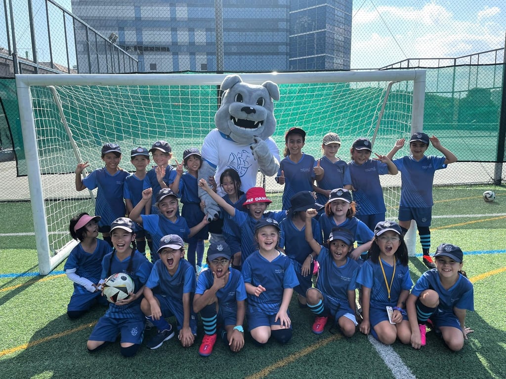 The U8 Girls Football Team are joined by the school mascot Winston at a competition featuring other international schools