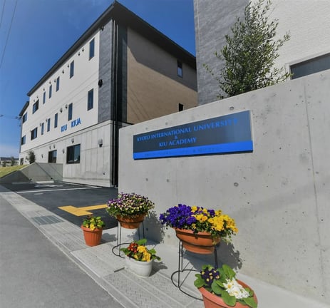 Exterior view of the KIU Academy campus featuring bright floral displays.