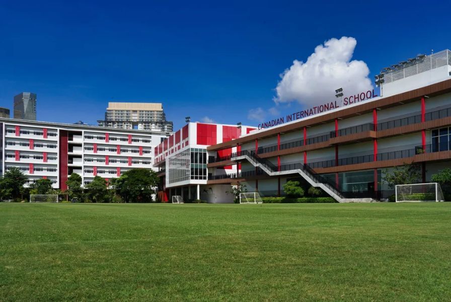 A view of the modern academic buildings and expansive green sports field.