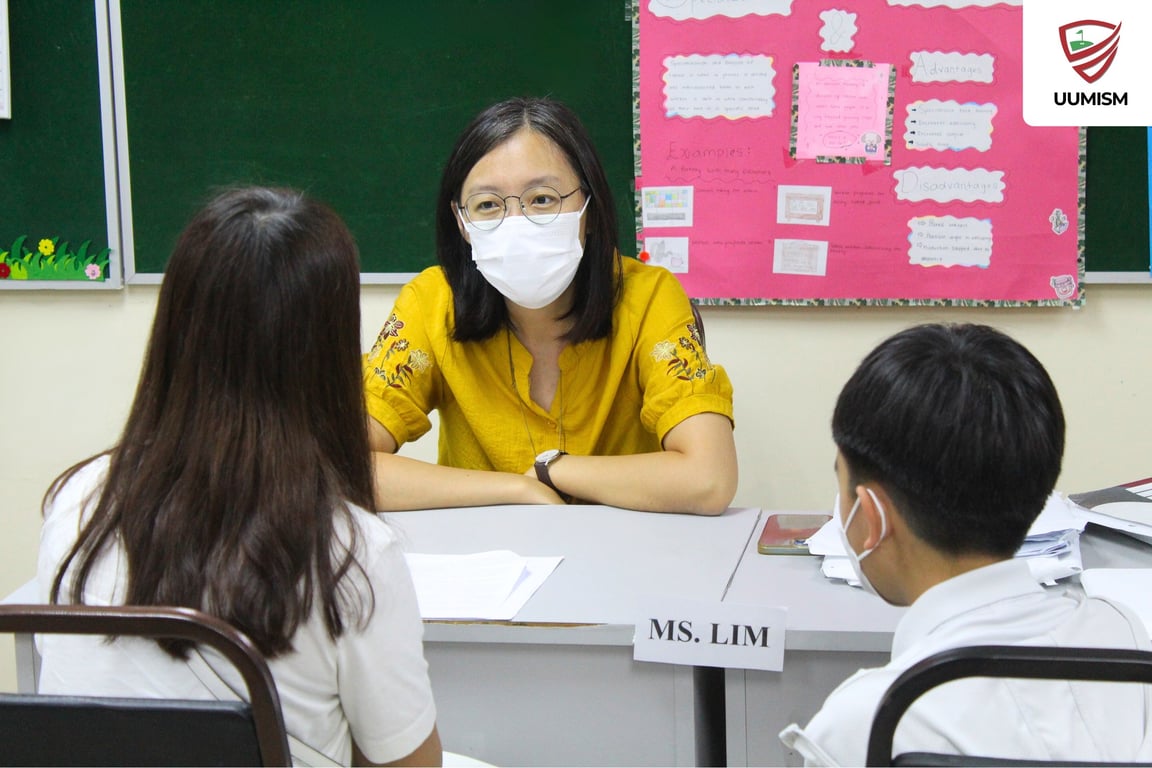 A teacher meets with a student and parent during the school’s Parent–Teacher Conference.