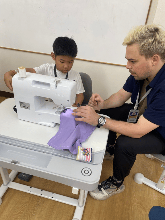 Teacher guides student in sewing activity.