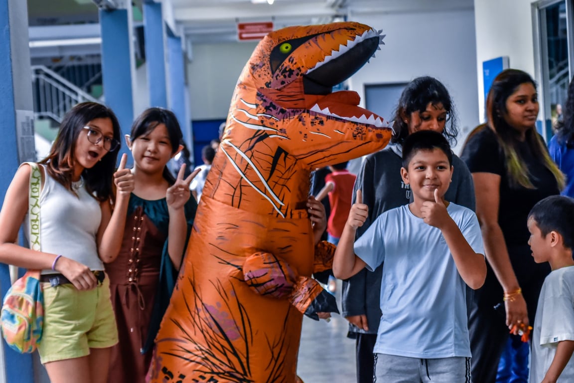 Students posing with a dinosaur costume during the Halloween.