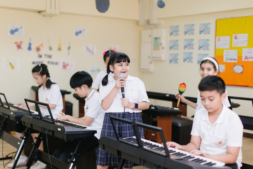 Students performing keyboard and vocal pieces in music class.