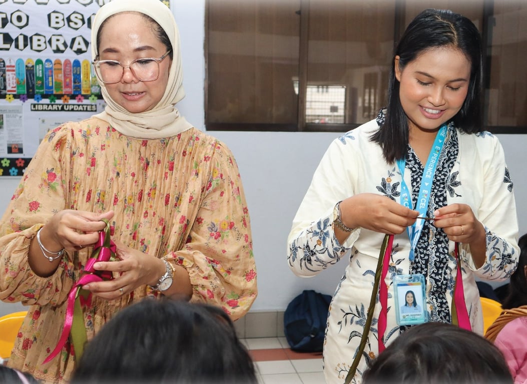 Teachers guiding students in a festive Raya activity.