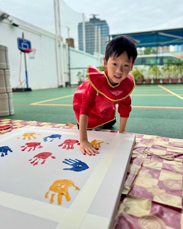 Child making handprint art during outdoor activity at school.