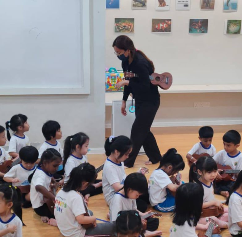 A teacher instructing the students how to play ukulele.