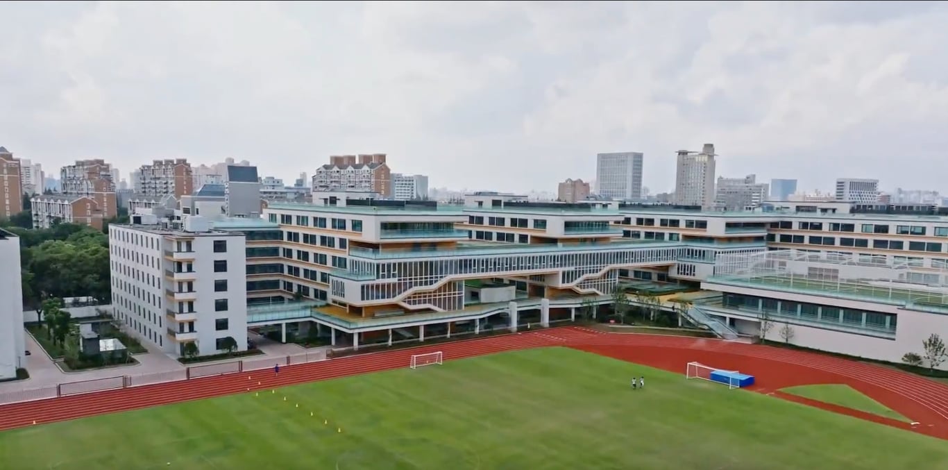 An aerial view of the sports field and modern SHSID campus buildings.