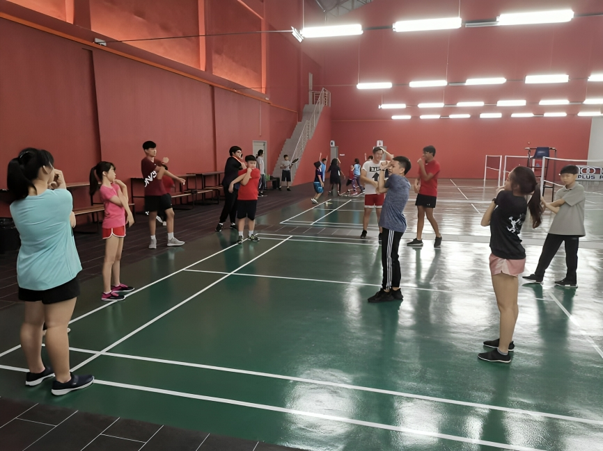 Warming up before starting badminton activities in the sports hall.