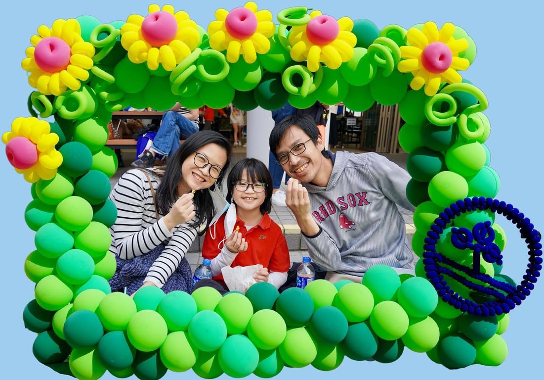 A family posing inside a balloon frame at the ICS 30th Birthday Bash.
