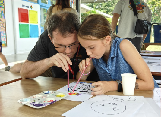 Parent and child collaborate on a painting during an art activity.