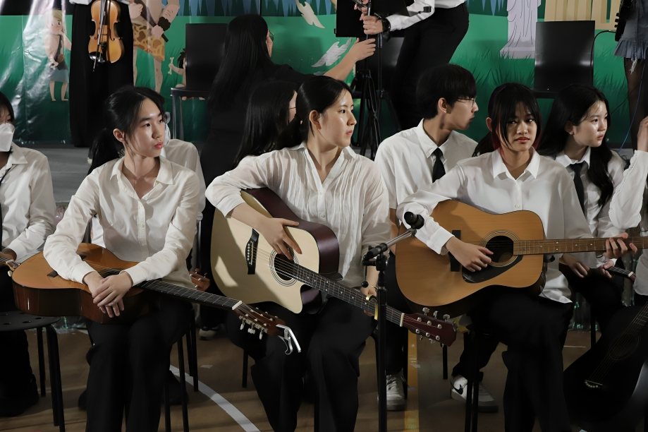Students prepare to perform with guitars during school concert.