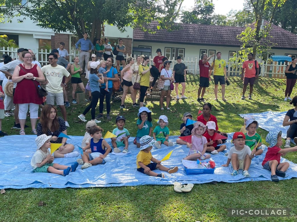 Children and families gathered on the lawn during Sports Day at Rain Trees International Kindergarten.
