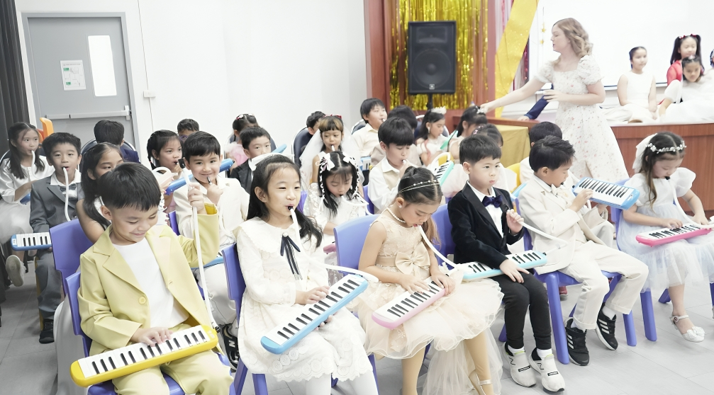 Students perform on melodicas during a school concert.