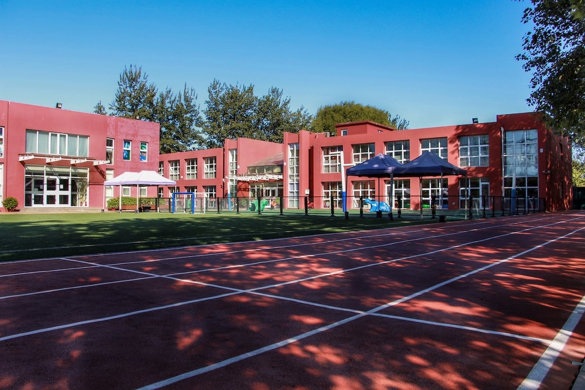 Modern school buildings overlooking the student athletic field and running track.