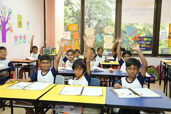 Students with their hands raised in a bright classroom