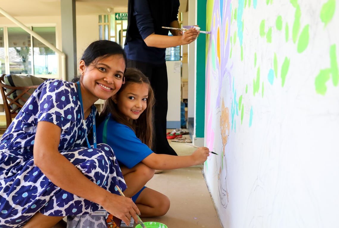 A parent along with her child painting a mural at UWC Thailand.