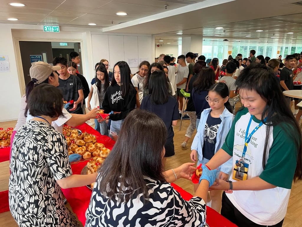 Students receiving traditional Swiss milk rolls prepared by the PTA during the GSIS Swiss National Day celebration.